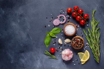 Herbs and condiments on black stone background.