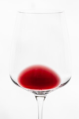 Horizontal close-up picture of an isolated bowl and a part of stem of transparent wine glass wine with a little of red wine in it on the white background