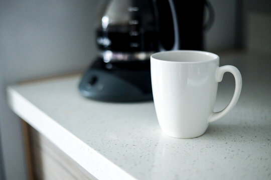 White coffee cup in front of coffee maker