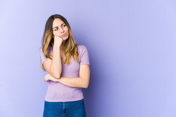 Young caucasian woman isolated on purple background who feels sad and pensive, looking at copy space.