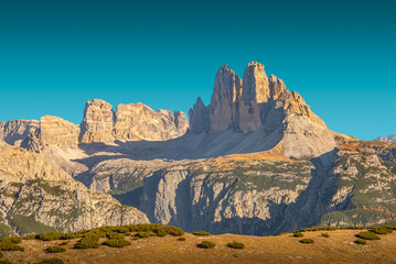 Beautiful sunset in magical Three Dolomite peaks at the national park Three Peaks (Tre Cime, Drei Zinnen) in Autumn colors at blue sky, South Tyrol, Italy, details