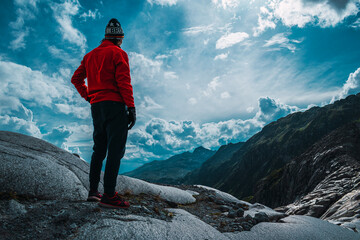 Chico con chaqueta roja en montañas de un glaciar