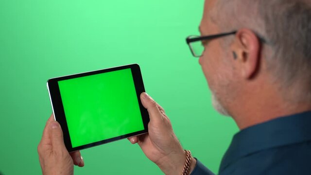 Green screen background with tablet also having green screen of man talking to someone over video call on his tablet computer.