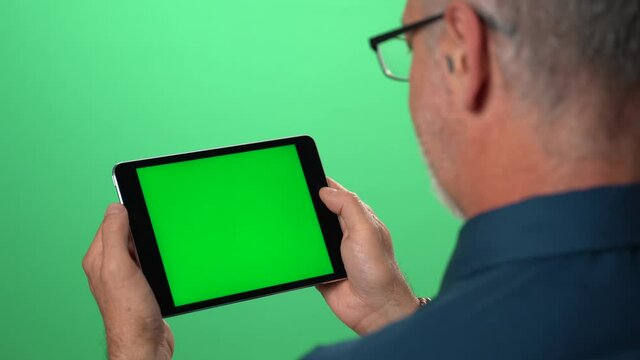 Green screen background with tablet also having green screen of man talking and using hand gestures to someone over video call.
