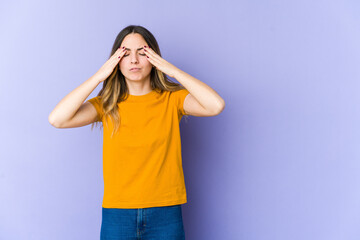 Young caucasian woman isolated on purple background having a head ache, touching front of the face.