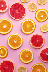 Round slices of grapefruit, orange and lemon on a pink background