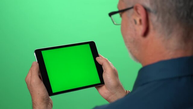 Green screen background with tablet also having green screen of man talking to someone over video call on his tablet computer.