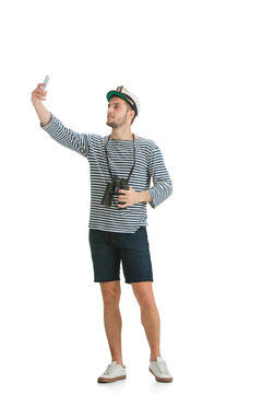Taking selfie. Caucasian male sailor in uniform on white studio background. Young man using modern devices and gadgets in his work. Concept of tech, professional occupation, job of seaman.