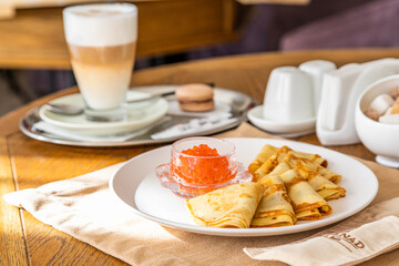 traditional Russian dish. Pancakes with red caviar and coffee. A set table in the background.