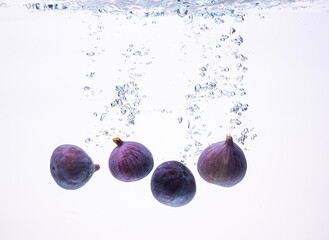 Fresh figs falling into the water isolated on white background. Food photography.