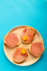 Sandwiches with ham and cherry tomatoes on a round wooden board.