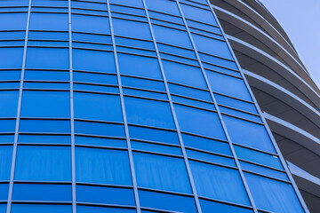 Obraz premium The bright blue sky is reflected in the windows of a modern glass building. Abstract fragment of a modern building. Sunny day.