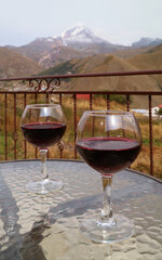 Two Glasses of Red Wine on a Glass Table with the Snow Capped Mountain in Background
