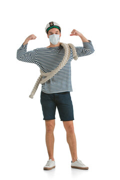Strong, healthy. Caucasian male sailor in uniform on white studio background. Young man using modern devices, binoculars, wearing face mask. Concept of tech, professional occupation, job of seaman.