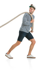 Pulls the rope, tug of war. Caucasian male sailor in uniform on white studio background. Young man using modern devices and gadgets. Concept of tech, professional occupation, job of seaman, emotions.