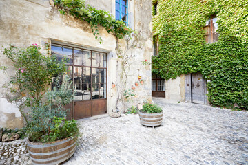 A 2020 view of an old house in a quiet square with ivy and plants in Lagrasse, Languedoc, South of France
