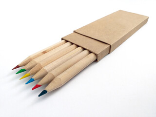 Colored tipped wooden pencils inside recycled paper case isolated on white background. Crayons with eco-friendly cover close up. School supplies and back to school pattern.