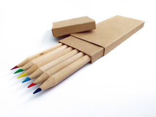 View of box of colored wooden pencils with separate lid and recycled paper. Biodegradable school supplies. Crayons with eco-friendly cover close up. Back to school pattern.