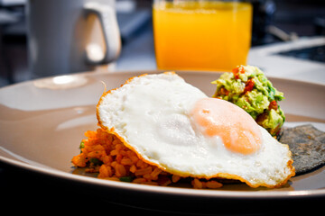 Delicioso desayuno tradicional mexicano, huevo con arroz, guacamole y tortilla de maíz azul. 