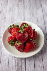 Fresh strawberries on a light wooden table on a plate