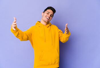 Fototapeta premium Young caucasian man isolated on purple background feels confident giving a hug to the camera.