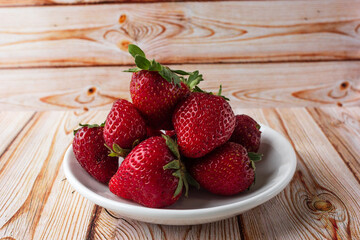 Fresh strawberries on a light wooden table on a plate