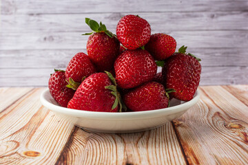 Fresh strawberries on a light wooden table on a plate