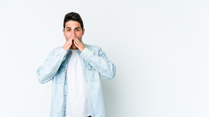 Young caucasian man isolated on white background shocked covering mouth with hands.