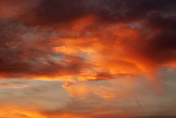 Dark blood red sky background. Dramatic heavy clouds with the hint of the sun at sunset. Many orange tones and patterns of clouds