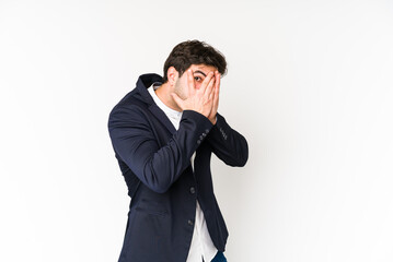 Young business man isolated on white background blink through fingers frightened and nervous.