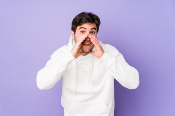 Young man isolated on purple background saying a gossip, pointing to side reporting something.