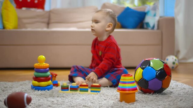 Little kid playing with colorful educational toys on carpet at home