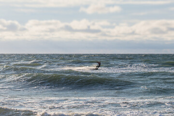 Professional kite surfer kite boarder rides the waves in the open sea, with a water splash, kitesurfing, kiteboarding extreme fun water sport in the summer sunny day