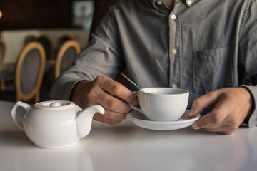 
The guy is drinking tea while sitting in a cafe