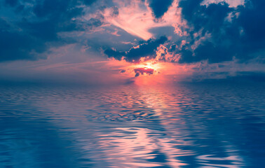 Evening sky with clouds, neon sunset, reflection in water, sea. The sun's rays through the clouds....