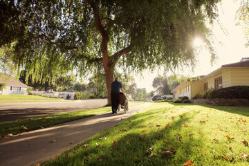 Elderly man on a residential sidewalk pushing his mate in a wheelchair