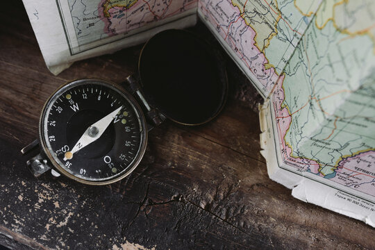 Compass lying on a wooden table next to the map