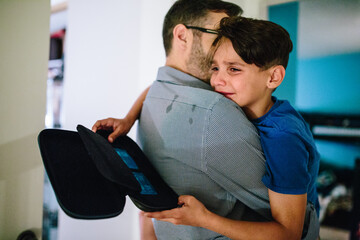 Father holds son who is crying while tears streak dad's shirt