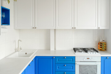 A modern bright kitchen with white and blue wardrobe.