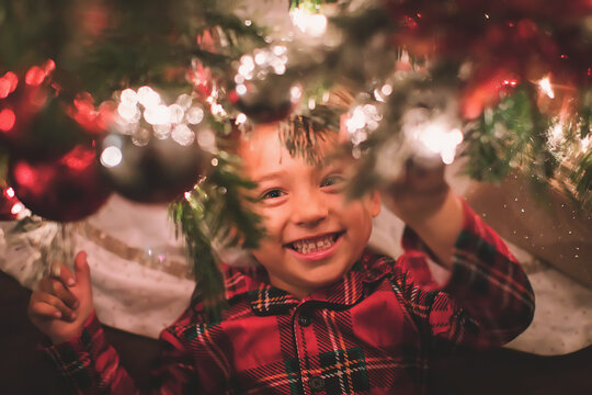 Boy hanging looking at camera under the Christmas Tree at night time