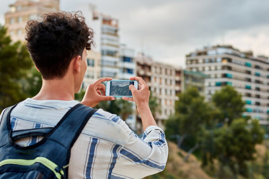 Close-up of a young afro-haired man is taking a photo with his mobile