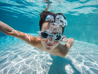 Underwater image of boy swimming in a pool with goggles on.