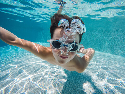 Underwater image of boy swimming in a pool with goggles on.