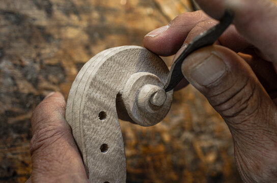 Violin maker luthier hand working a new violin scroll in Cremona Italy