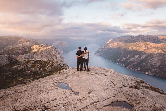 Couple standing at cliff at Preikestolen, Norway during sunset