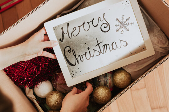 Crop person taking frame with Merry Christmas inscription from box