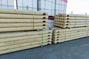 Wooden balk, timber, beam and building material stacked at construction site. Wooden planks, lining, boards for construction works in the sawmill. Construction of a wooden house