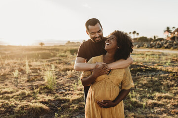 Young married couple embracing pregnancy at beach
