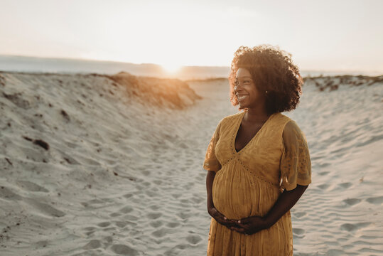 Portrait of pregnant mother in third trimester at beach at sunset - Powered by Adobe