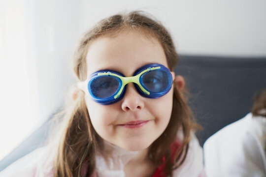 Happy girl in swim goggles resting on sofa